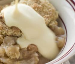 Ein Dessert mit Streuseln und Vanillesoße in einer Schale wird serviert.