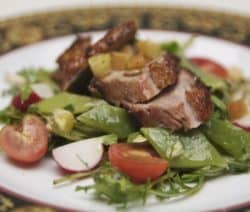 Ein Teller mit Salat, Zuckerschoten, Tomaten, Radieschen und gebratenem Fleisch.