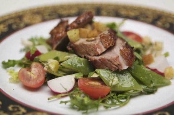 Ein Teller mit Salat, Zuckerschoten, Tomaten, Radieschen und gebratenem Fleisch.