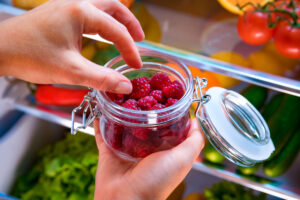 Kühlschrank richtig einräumen: Himbeeren in Einmachglas werden aus Kühlschrank genommen