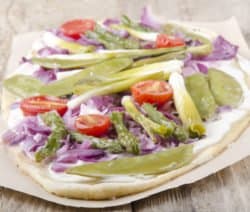 Flammkuchen mit grünem Spargel, Tomaten und Zwiebeln auf Holztisch.