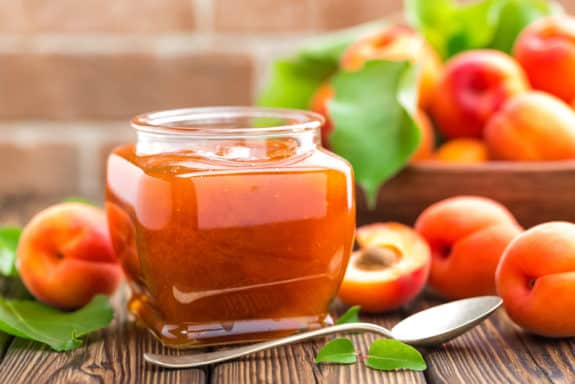 Apricot jam in a jar and fresh fruits with leaves