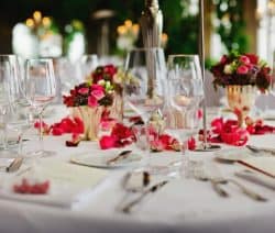Ein elegant gedeckter Tisch mit Blumenarrangement, Weingläsern und Besteck auf weißer Tischdecke.