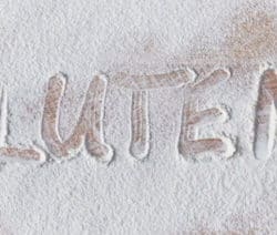 Holzbrett mit Mehl und das Wort Gluten