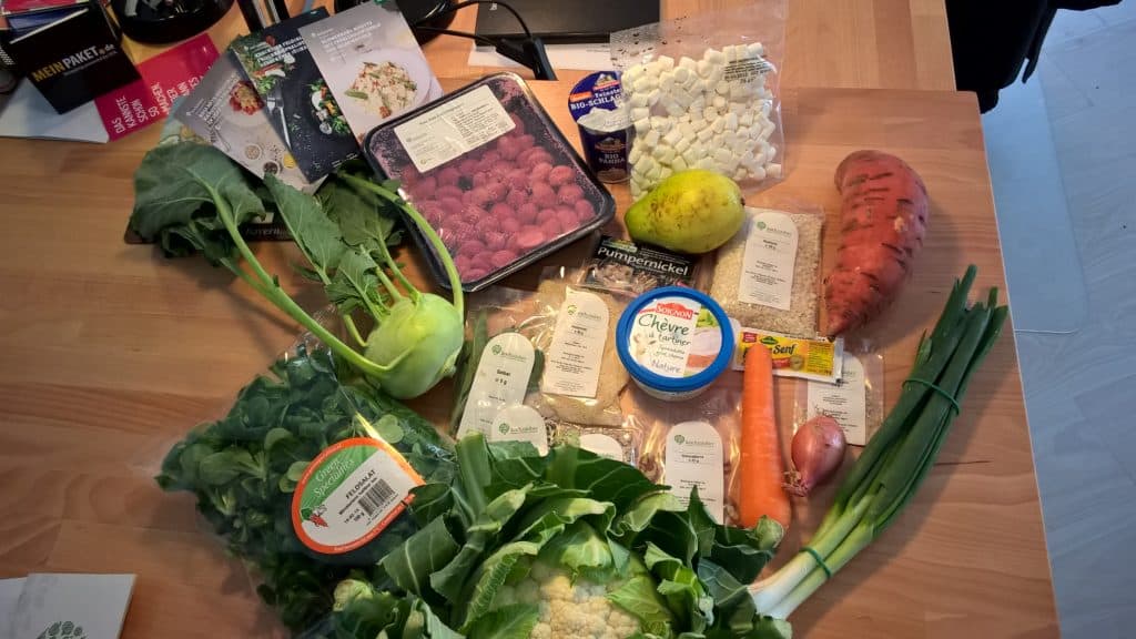 Verschiedene Lebensmittel auf einem Tisch: Gemüse, Obst, Brot, Käse und Gewürze.