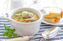 norddeutsche Fischsuppe in weißer Suppentasse mit Weißbrot im Hintergrund