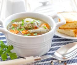 norddeutsche Fischsuppe in weißer Suppentasse mit Weißbrot im Hintergrund