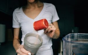 Frau mischt Proteinpulver in Shake