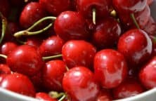 Eine Schale voller glänzender roter Kirschen mit grünen Stielen.