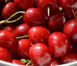 Eine Schale voller glänzender roter Kirschen mit grünen Stielen.