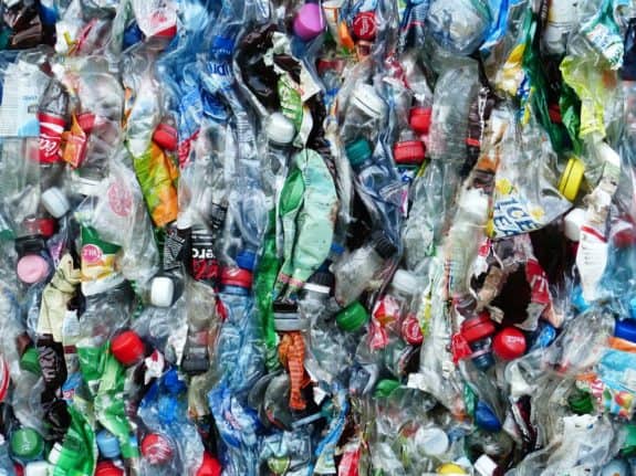 Gepresste Plastikflaschen mit bunten Deckeln, dicht gestapelt.