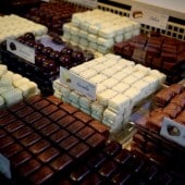 Verschiedene Pralinensorten in weißen und dunklen Schokoladen, ordentlich in Reihen auf einem Marktstand angeordnet.