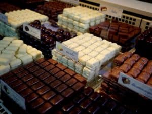 Verschiedene Pralinensorten in weißen und dunklen Schokoladen, ordentlich in Reihen auf einem Marktstand angeordnet.