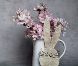 leckeres Osteressen: Blumenvase mit aus Holz geschnitztem Hasenkopf davor