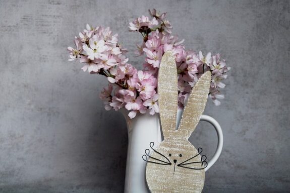 leckeres Osteressen: Blumenvase mit aus Holz geschnitztem Hasenkopf davor