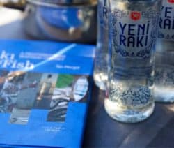 Buch 'Raki and Fish' neben zwei Yeni Raki-Flaschen auf einem Tisch.