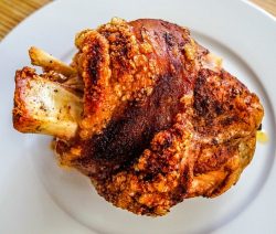 Knusprige Schweinshaxe auf einem weißen Teller.