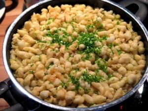 Frische Spätzle in einer Pfanne, garniert mit gehacktem Schnittlauch.