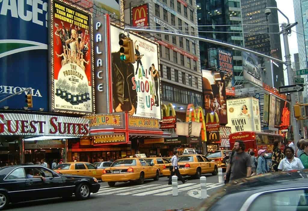 Belebte Straßenszene am Times Square mit hellen Werbetafeln und gelben Taxis.