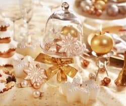 Festliche Weihnachtsdekoration mit Keksen, goldenen Kugeln, Kerzen und Schneeflocken auf einem Tisch.
